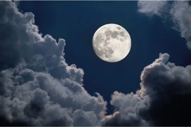 雲間から顔をのぞかせる満月の夜空