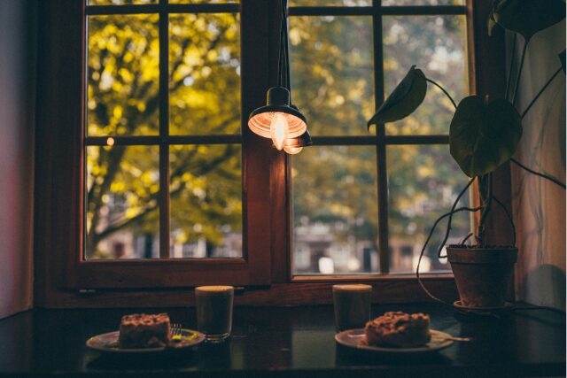 窓辺のテーブルに並ぶコーヒーとケーキ。秋色の景色を眺めながら過ごす穏やかな時間