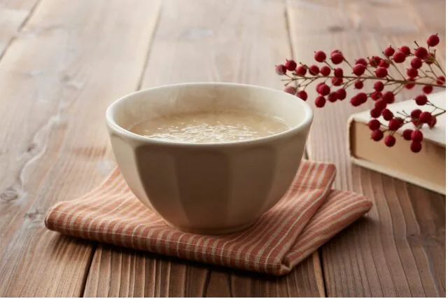 木のテーブルの上にリネンの布と陶器の器が置かれた、あたたかみのある秋のテーブルシーン。