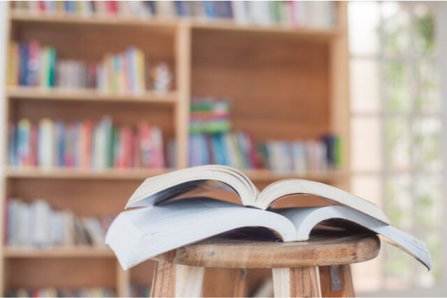 書店の一角で、椅子の上に開かれた本。背景にカラフルな本棚がぼんやり映る