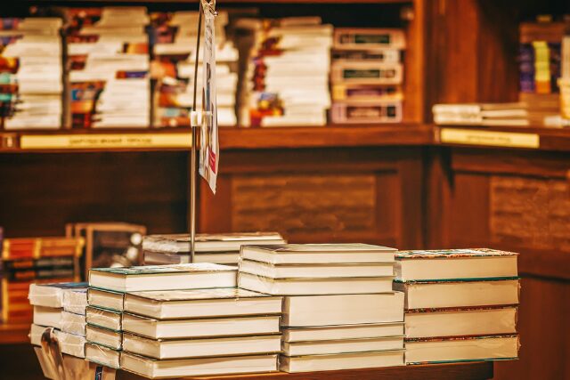 書店のテーブルに平積みされた新刊本。背景には温かみのある木の本棚