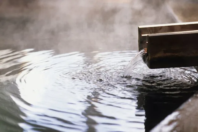 湯口から湯が注がれ、静かに波紋が広がる温泉の水面